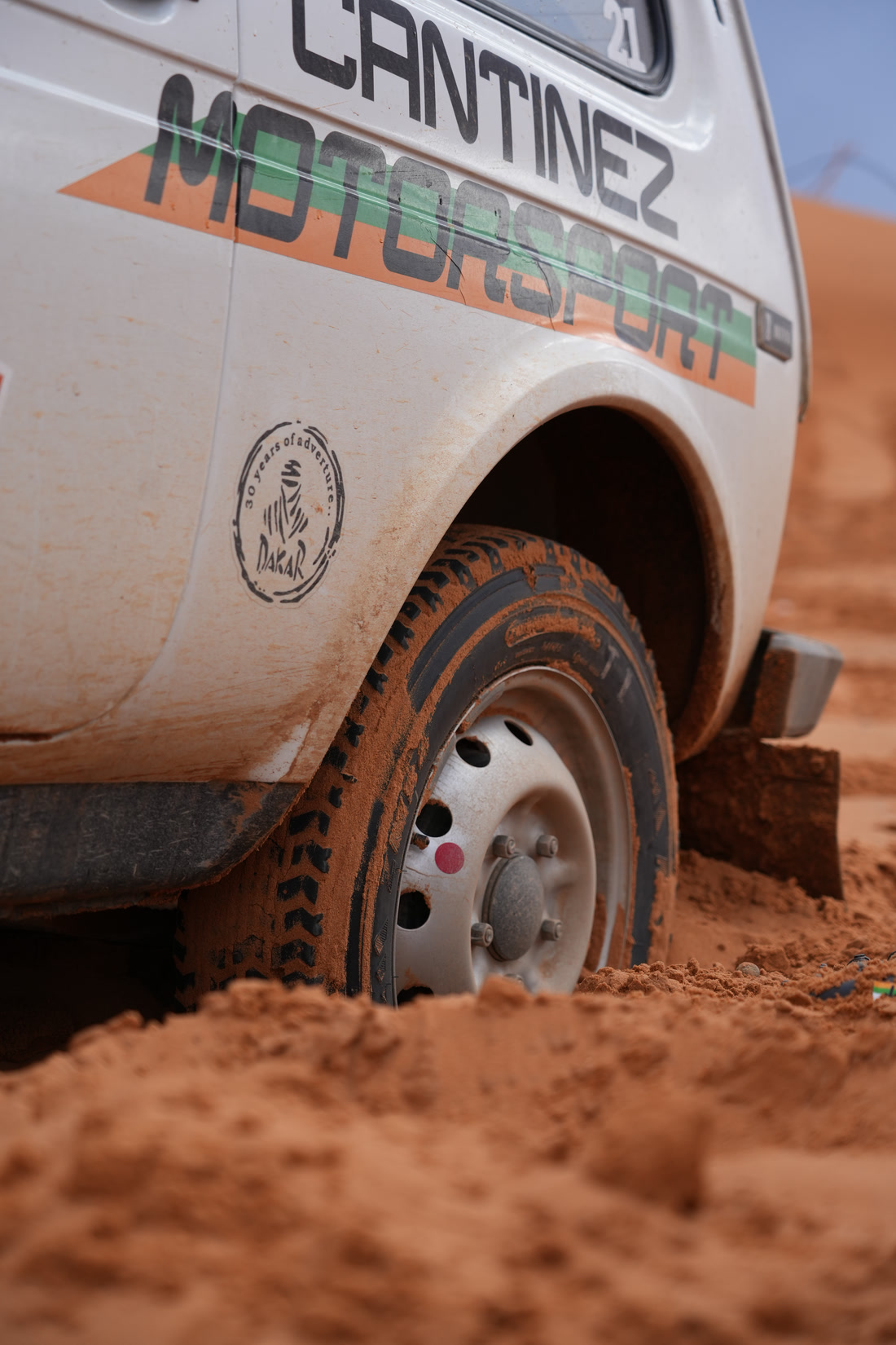 Coche de rally con la rueda hundida en la arena de las dunas